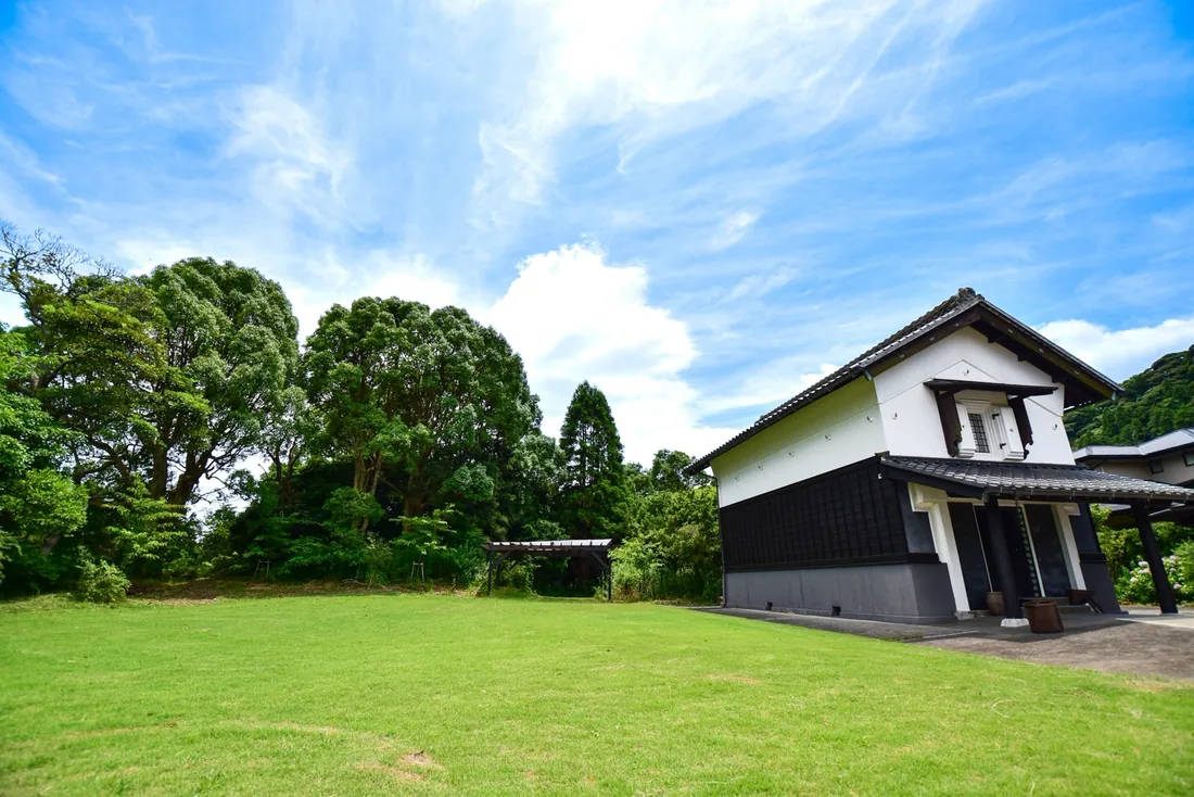 白壁と黒板壁の土蔵と、前に広がる芝生